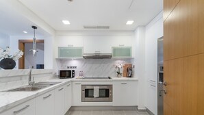 Une cuisine moderne avec des meubles blancs, un four encastré, un four à micro-ondes et un évier.