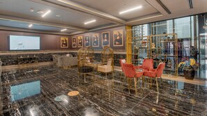 A lobby with marble flooring, a large screen, framed artwork, and seating areas. - Warm 1-bedroom Family-friendly Aparment in JLT (Dubai)