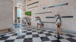 A lobby with a checkered floor, three horse statues, and a green wall. - Warm 1-bedroom Family-friendly Aparment in JLT (Dubai)
