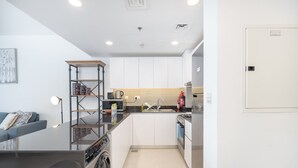 A compact kitchen with white cabinets, a built-in oven, and a dishwasher. - Elegant 2-bedroom Apartment in Dubai South Close to Expo 2020 (Dubai)