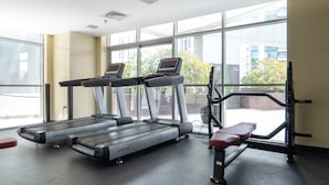 A gym with treadmills, a bench, and exercise equipment. - Bright 1-bedroom With View Dubai Marina (Dubai)