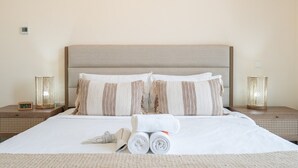 A neatly made bed with a beige headboard, two bedside tables with lamps, and a digital clock. - Boho-inspired 1 bed in Production City (Dubai)
