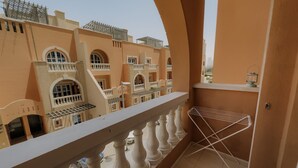 Un balcón con barandilla blanca, un tendedero de metal y vistas a edificios vecinos con balcones.