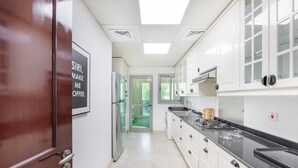 Una cocina moderna con armarios blancos, un refrigerador de acero inoxidable, una estufa a gas y un ventanal sobre el fregadero.