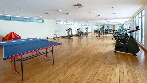 Un gimnasio amplio con ping pong, cintas de correr y bicicletas estáticas.