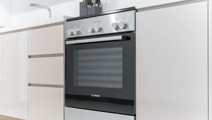 A modern kitchen with a Bosch oven, stainless steel cabinets, and a white countertop. - Elegant 1BR in Business Bay Sleeps 4 Near Downtown (Dubai)