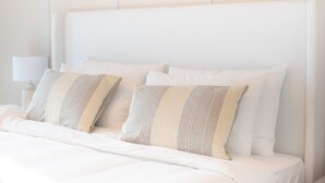A neatly made bed with white bedding and striped pillows. - Trendy 1-bedroom Apartment With Stunning Views at MBL Residences JLT (Dubai)