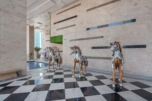 A lobby with a checkered floor, three metallic horse statues, a pool, and a green wall. - Trendy 1-bedroom Apartment With Stunning Views at MBL Residences JLT (Dubai)