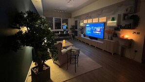 Una sala moderna con un televisor de pantalla plana, un comedor y una planta grande en maceta.