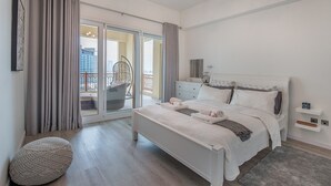 Un dormitorio moderno con una cama grande, un balcón con una silla y vistas a la ciudad.
