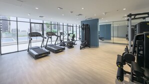 A modern gym with treadmills, elliptical machines, and weightlifting equipment. - Immaculate Studio Great for 2 in Meydan (Dubai)