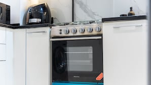 A kitchen with a stainless steel oven, a coffee maker, and a marble backsplash. - Elegant 1-bedroom Apartment in Jumeirah Village Triangle With Balcony Bliss (Dubai)