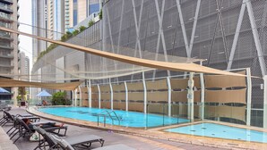 Et poolområde med liggestole og swimmingpool, omgivet af hegn og overdækket af et markise.