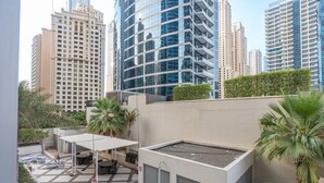 A rooftop terrace with a geometric tile pattern, outdoor seating, and palm trees. - Stylish 1BR Urban Living in Dubai Marina (Dubai)