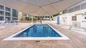 A swimming pool with a tiled deck, lounge chairs, and a covered area with a canopy. - Stylish 1BR Urban Living in Dubai Marina (Dubai)