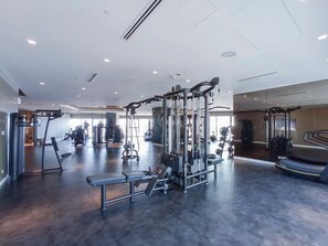 Une salle de sport moderne équipée de divers appareils d’exercice, d’un banc et d’un tapis de course.