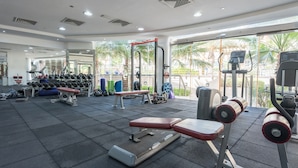 A gym with weightlifting equipment, benches, and a mirrored wall. - Spacious Studio at Imperial Residence in JVT That Sleeps 4 (Dubai)