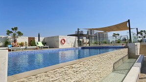 A swimming pool with a stone wall, a lifebuoy, and a shaded area.