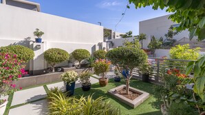 Un jardin sur le toit, agrémenté de plantes en pot et d’une petite pelouse.