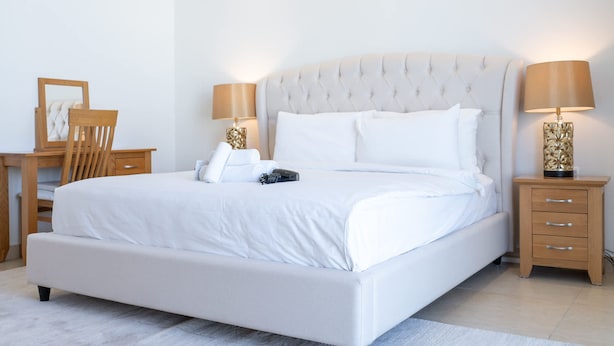 Une chambre bien rangée, avec un grand lit, des tables de chevet, un bureau et une chaise.