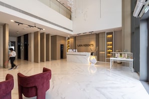 Un hall d’entrée spacieux avec un comptoir de réception portant l’inscription « Laya Heights », un sol en marbre et un mobilier moderne.