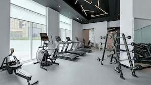 A modern gym with treadmills, elliptical machines, and weightlifting equipment. - Stylish Studio Apartment in Tecom s Prime Location (Dubai)