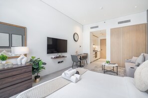 Een moderne hotelkamer met een bed, televisie, bureau en zithoek.