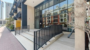 Un edificio moderno con facciata in vetro, terrazza in legno e ringhiera nera.