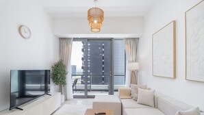 Ein modernes Wohnzimmer mit Flachbildfernseher, Couch, Holztisch und großem Fenster mit Blick auf die Stadt.