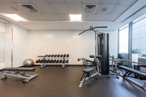 Une salle de sport équipée de machines d’exercice, d’haltères et d’un banc.