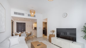 Ein modernes Wohnzimmer mit Sofa, Couchtisch, Fernseher und Essbereich.