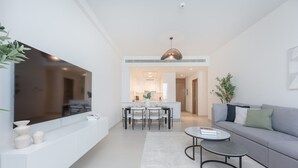 A modern living room with a sofa, coffee table, and dining area. - Elegant Relaxing 3-bedroom Apartment in Perfect Location at Canal Front 6 (Dubai)