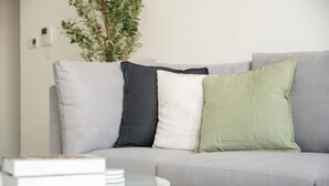 A living room with a grey sofa, a round coffee table, and a stack of books. - Elegant Relaxing 3-bedroom Apartment in Perfect Location at Canal Front 6 (Dubai)