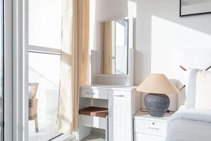 A hotel room with a white desk, a mirror, a lamp, and a bed. - Beautifully Furnished Studio With Skyline Views (Dubai)