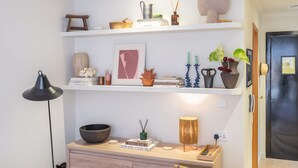 Ein ordentlich eingerichteter Raum mit einem Holzschrank, einer schwarzen Lampe und Regalen mit Dekoration und Büchern.