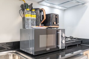 A kitchen with a black toaster oven, a sink, and a countertop. - Stay in Alexis Tower s Stunning Studio and Sleeps 2 (Dubai)