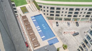 An aerial view of a hotel with a rooftop pool, a parking area, and a building with multiple floors and windows. - 1606 DEC Tower 1 in Dubai (Dubai)