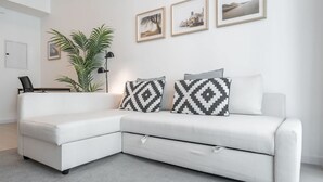 A white sectional sofa with a small table and a potted plant in a modern living room with a light-colored carpet. - 1606 DEC Tower 1 in Dubai (Dubai)