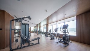 Un gimnasio amplio con diversos equipos de ejercicio, ventanas grandes y un diseño moderno.