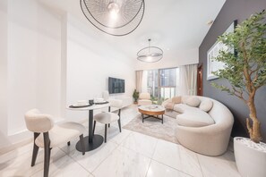 A modern living room with a round coffee table, a sofa, and a dining area with chairs and a table set for two.