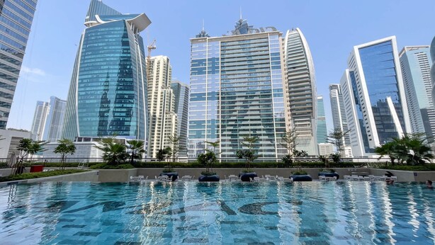 A swimming pool with lounge chairs and a cityscape of modern high-rise buildings in the background. - 426 Zada Tower in Dubai (Dubai)
