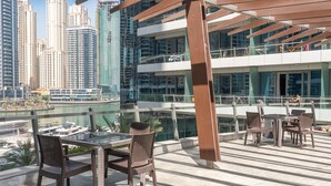 A rooftop terrace with wicker furniture, a glass table, and a view of the marina and city skyline. - 1608 Siverene Tower A (Dubai)