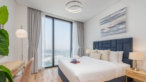 Ein modernes Hotelzimmer mit einem großen Bett, einem Schreibtisch, einem Stuhl, einem Nachttisch mit Lampe und Blick auf die Stadt.