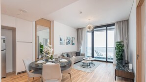 Ein modernes Wohnzimmer mit Essbereich, einer Couch, einem Couchtisch und einem großen Fenster mit Vorhängen.