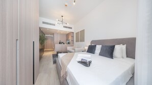 A modern hotel room with a large bed, a small seating area, and a kitchenette in the background. - 518 Bali Residence in Dubai (Dubai)