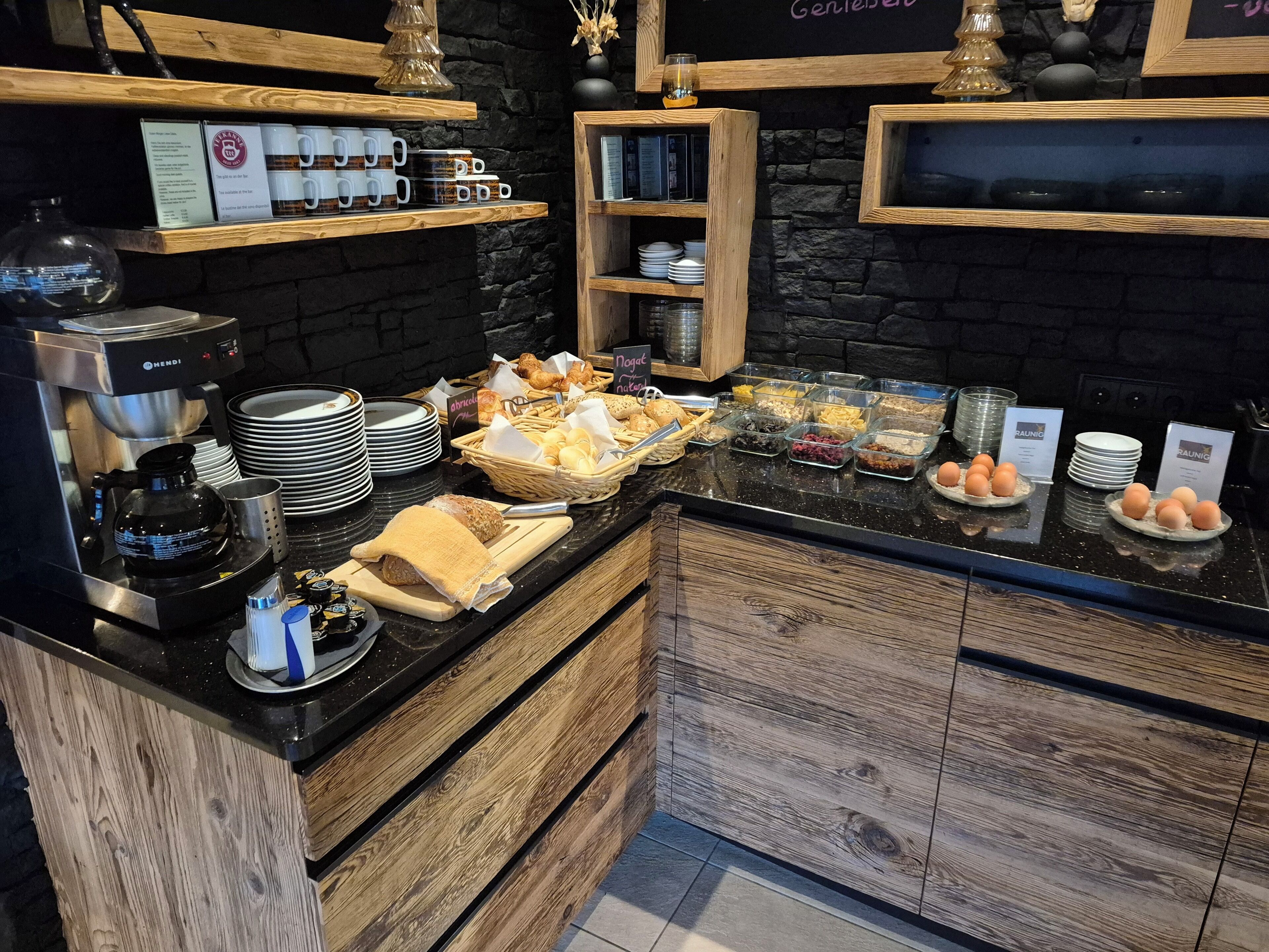 A breakfast buffet with various food items, coffee machines, and neatly arranged plates and bowls.