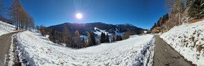 Carretera nevada en la montaña, cielo despejado y sol brillante.