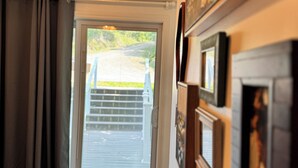 Una habitación con puerta corredera de vidrio que da a un espacio exterior cubierto, un refrigerador y un cuadro colgado en la pared.