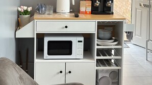 A kitchen with a microwave, a coffee maker, and a TV mounted on the wall. - The Garden Studio (Luton)