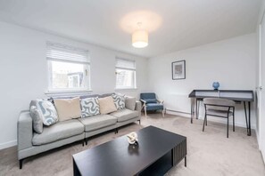 A modern living room with a sofa, coffee table, and a desk with a chair. - The Gordon | Vacant Nests | Heart of Aberdeen (Aberdeen)